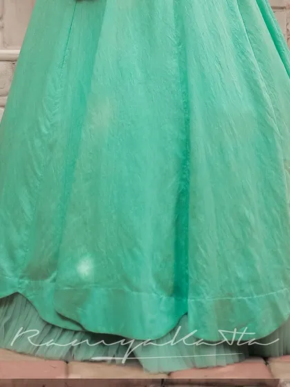 The hem of the turquoise lehenga, showing the layered construction with a net under-skirt that provides volume and a graceful fall.