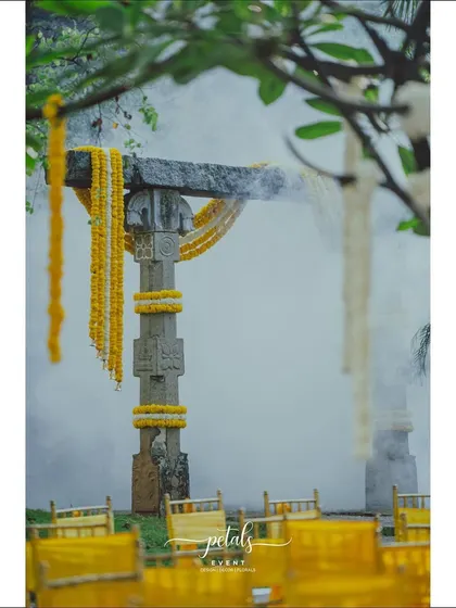 A stone pillar is adorned with marigold garlands, with smoke adding a mystical touch to the scene.