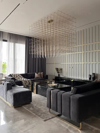 The main seating area of the entertainment lounge, featuring channel-tufted velvet sofas, a black marble coffee table, and a dramatic grid-like chandelier. The fluted wall with brass inlay adds another layer of refined detail.