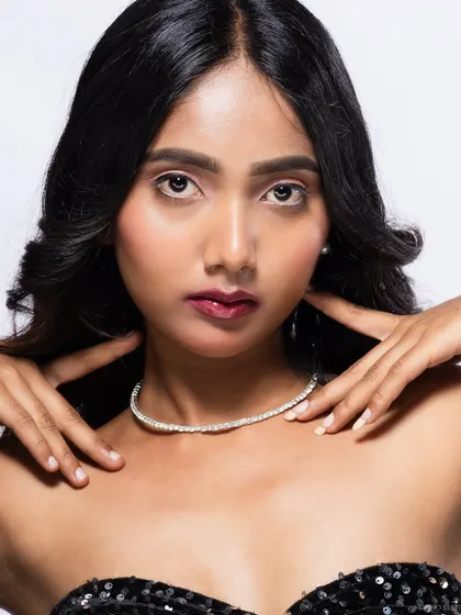 A beauty close-up of a model in a sequined top, with a direct and engaging gaze.