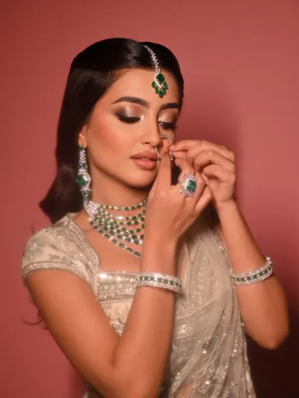 The final touches are just as important. Here, the bride adjusts her nose ring, showing a candid moment where the full artistry, from the glowing skin to the detailed jewellery, comes together.