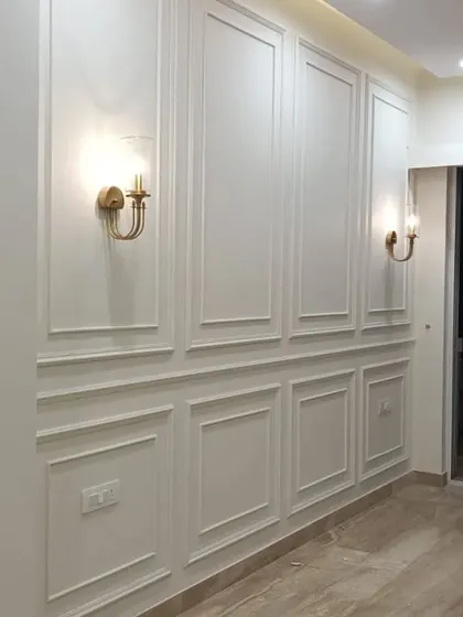 This image showcases classic wall molding painted in crisp white, accented with vintage-style brass wall sconces. This detail adds a timeless elegance to the corridor.