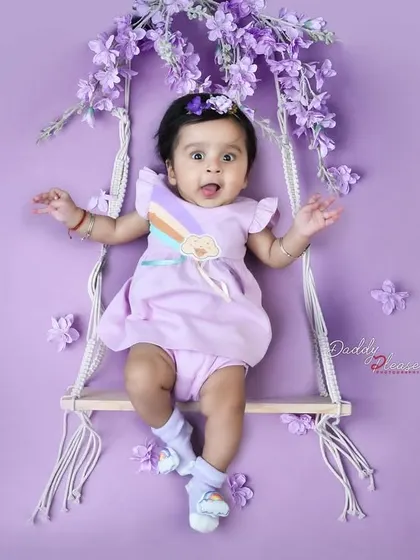 Capturing the playful personality of a baby girl as she makes a funny face while sitting on a floral swing. These candid moments are just as precious as the posed ones.