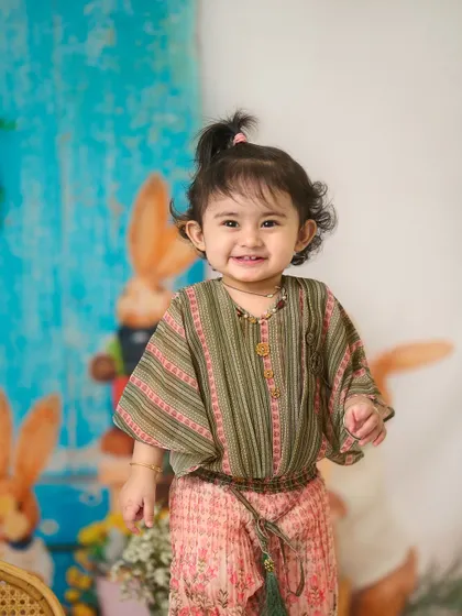 A happy smile in the studio. This portrait showcases a different pose from the same colorful Easter-themed setup, showing the variety we can capture in one session.