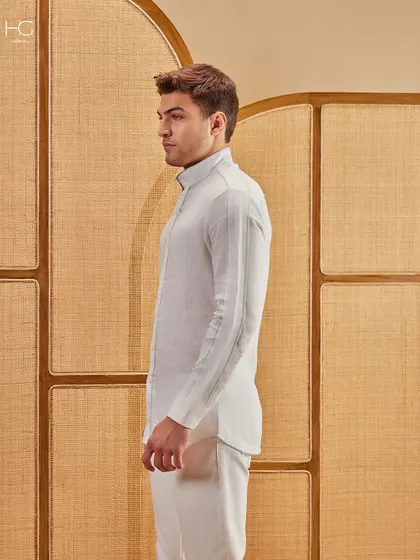 A side profile of the crisp all-white shirt and trousers, showcasing the clean, tailored lines that create a look of effortless confidence.
