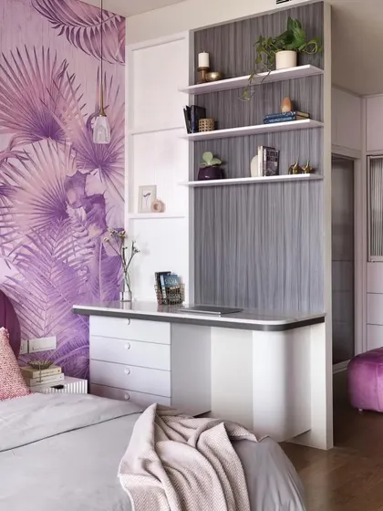 The master bedroom includes this integrated study and storage unit. The grey wood-textured laminate and white shelves tie into the room's purple theme, while the purple pouffe from the walk-in closet is visible.