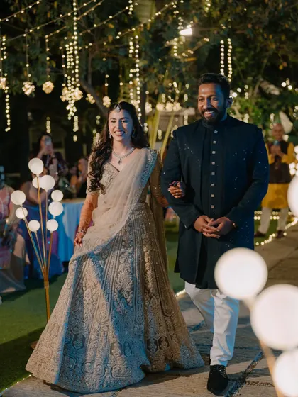 A beautiful shot of the bride walking down the aisle at her outdoor reception. The soft glam makeup looks stunning under the fairy lights.