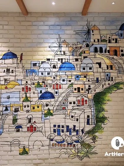 A charming doodle art mural depicting a Santorini-style village, painted directly onto an exposed brick wall. This piece adds a touch of Mediterranean whimsy and is a great conversation starter.
