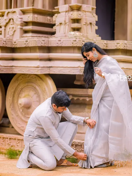 A sweet, chivalrous moment captured by the stone chariot. The groom helps his bride with her shoe, a small, tender gesture that tells a beautiful story.
