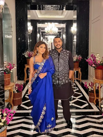 A happy couple posing in the grand floral entryway we designed. Our decor creates the perfect backdrop for capturing beautiful memories of your special day.