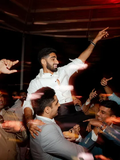 The groom is lifted up by his friends on the dance floor in a moment of pure celebration. This high-energy shot captures the fun and excitement of the wedding after-party.