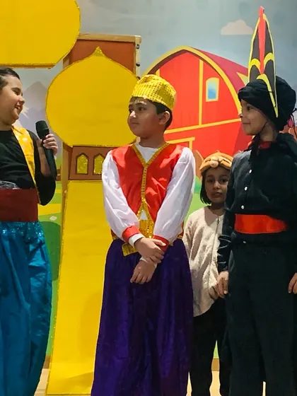 The cast of the Aladdin show interacts on stage during a key moment in the story.