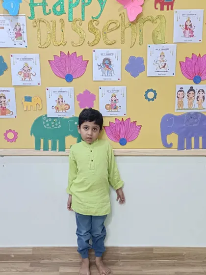 A little one stands proudly in front of our Dussehra decorations. Celebrating festivals helps children connect with their cultural roots from an early age.