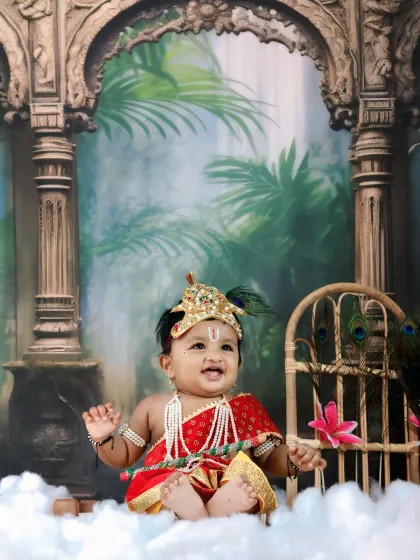 A happy baby Krishna sits among fluffy clouds in our studio, smiling brightly for the camera.