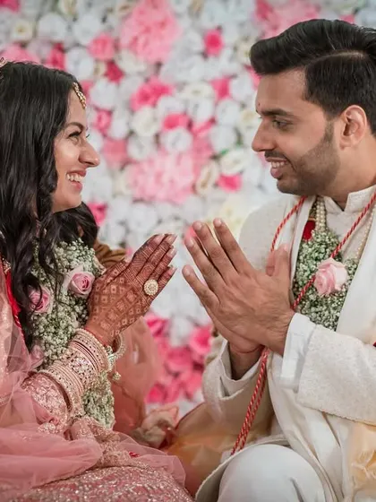 A moment of mutual respect and playfulness during the ceremony. The couple greets each other with a "namaste," sharing a sweet smile.