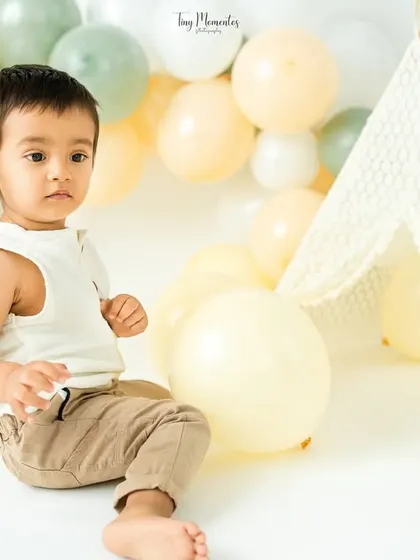 A quiet moment of observation in the boho-themed setup, complete with a lace teepee and soft, earthy-toned balloons.