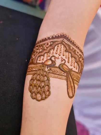 A close-up of a delicate peacock armlet, a beautiful and elegant addition to any bridal mehendi design.