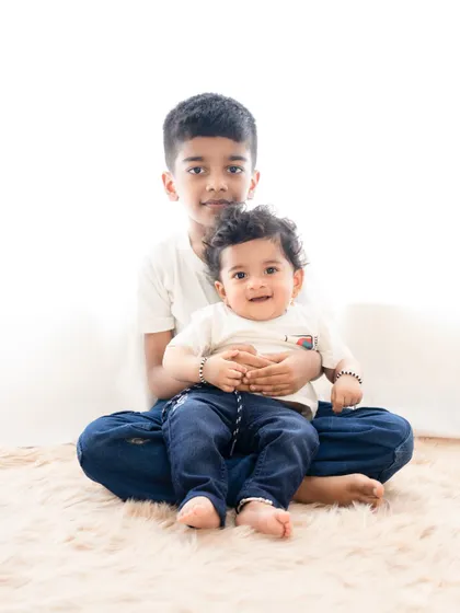 A sweet and simple portrait of two brothers. The older brother gently holds his baby brother, showing his protective and loving nature.