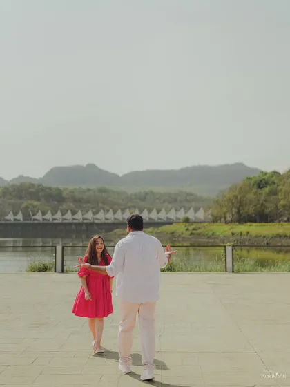 A wide shot capturing the couple in a beautiful, expansive landscape at Aamby Valley, with the mountains and lake creating a stunning backdrop.