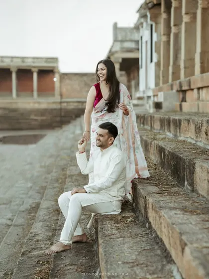 A candid moment of laughter on the steps of a temple, capturing the genuine connection and happiness between the couple during their traditional pre-wedding shoot.