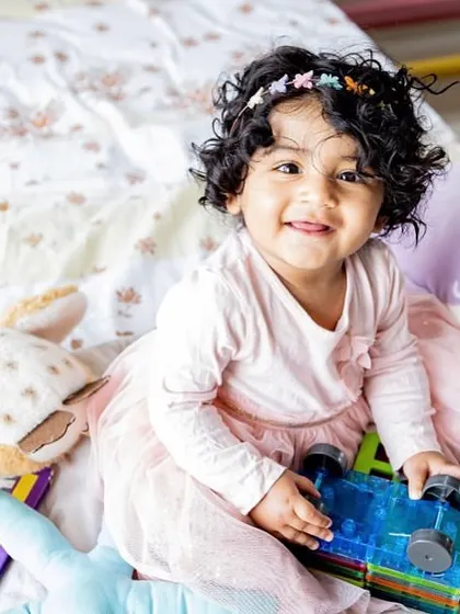 This little girl's smile is infectious as she plays with her favorite toys. Toddler sessions are all about capturing their budding personality and gorgeous curly hair.
