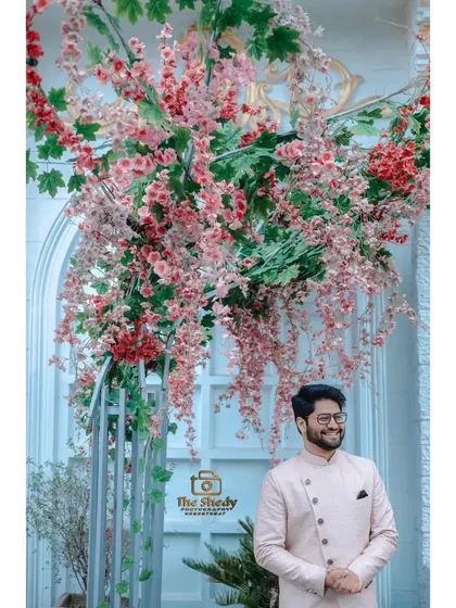 A happy groom surrounded by beautiful floral decorations at his engagement ceremony. This shot captures the festive and joyful mood of the event.