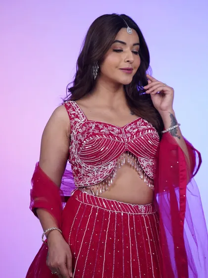 A close-up of the hot pink lehenga, focusing on the stunningly detailed blouse and the delicate maang tikka. It's a look that's ready for its close-up.