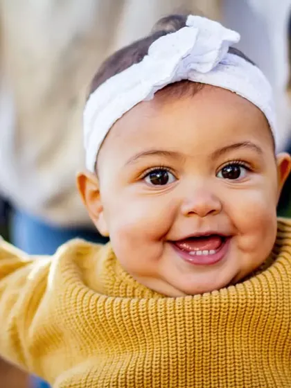 That big, gummy smile is just the best. This close-up captures the pure happiness of a baby who is learning to stand with a little help.