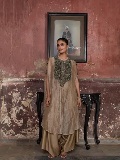 A model stands gracefully in a beige cape set, her look a perfect blend of tradition and modernity.