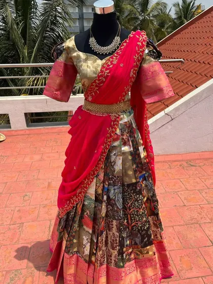 A traditional half saree with a patchwork Kalamkari skirt and a bright pink embroidered dupatta.