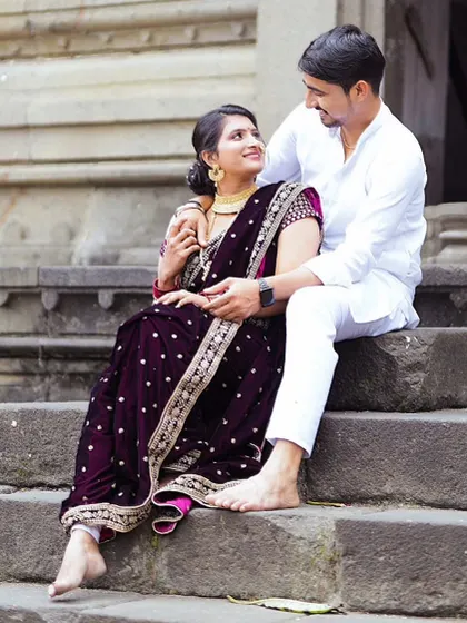 A traditional and loving portrait. The groom's simple white kurta complements the bride's ornate Navari saree, creating a timeless and culturally rich image.
