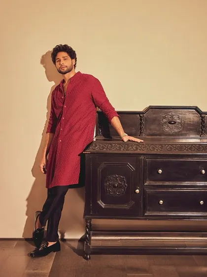 Siddhant Chaturvedi in a textured red kurta by Kunal Rawal. Paired with black trousers and loafers, this is a perfect example of a smart, contemporary look for the festive season.