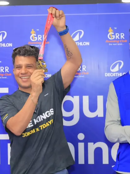 A finisher holding his medal high. This is the look of a man who has been through the fire and come out stronger.