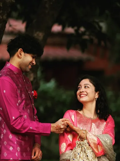 A smiling couple shares a sweet moment amidst the lush greenery and floral decor of their Mehendi celebration.