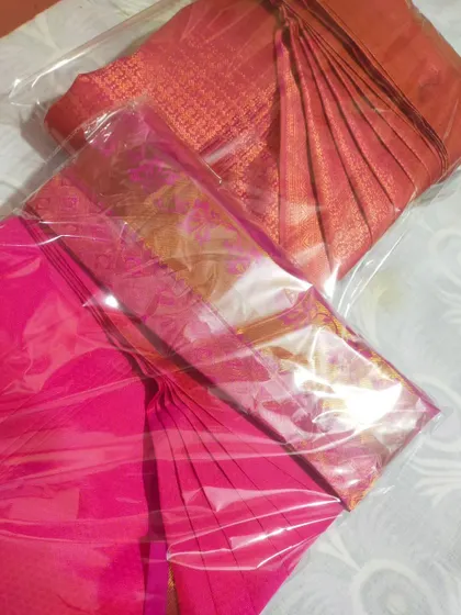 A pink and an orange saree, both packed and ready. The clear packaging makes it easy to see which saree is inside.