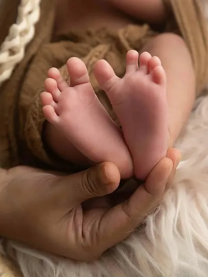 A close-up of perfectly tiny newborn toes, held gently in a mother's hand. These detail shots are just as important as the full portraits.