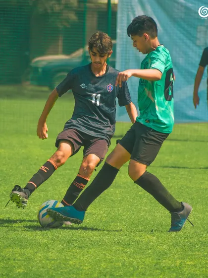A tough tackle between two determined U-13 players.