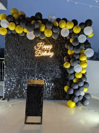 This wide shot shows how the sequin wall and balloon arch create a defined party corner on an open rooftop.