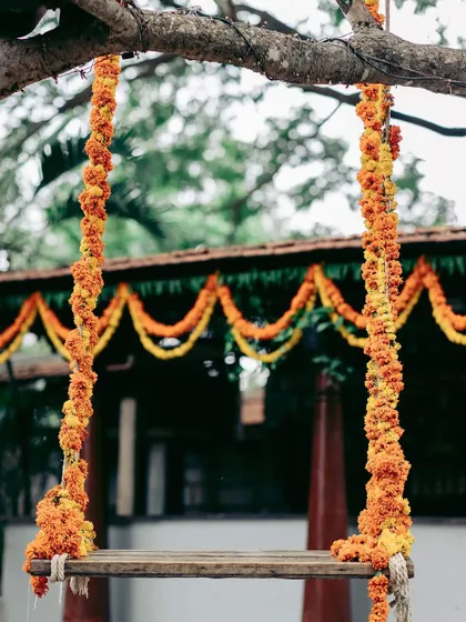 A floral swing decorated with bright orange and yellow marigolds, perfectly capturing the vibrant and energetic spirit of a Haldi or Mehendi ceremony.