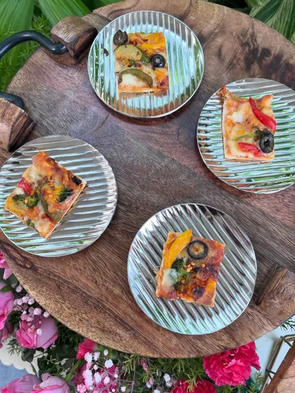 Mini pizzas on silver-striped plates, offering a familiar and delicious bite for guests at a relaxed pool party.