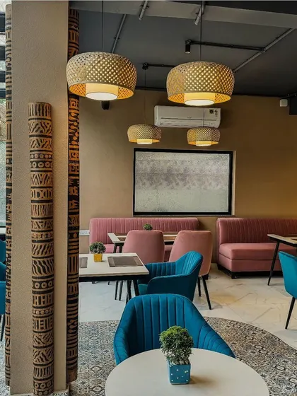 The dining area at Papyrus, where earthy tones, vibrant teal and pink chairs, and bamboo pendant lights come together to create a warm and eclectic Egyptian-inspired ambiance.