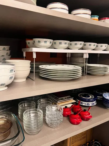 Using an adjustable shelf riser, I've doubled the storage space in this cabinet. The dinner plates are stacked below, while the matching bowls are organized on top, making the entire set easy for staff to access.