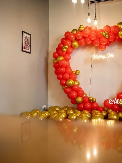 This wide shot shows the full impact of our heart-shaped proposal decor in a cafe setting. The floor covered in gold balloons adds an extra layer of celebration to the surprise.