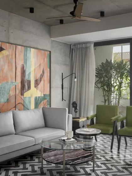 The ground-floor lounge in Swatantra Residence provides an inclusive space for the family. The edgy design of the concrete walls merges perfectly with splashes of color from the furniture and artwork, offering style, comfort, and functionality.
