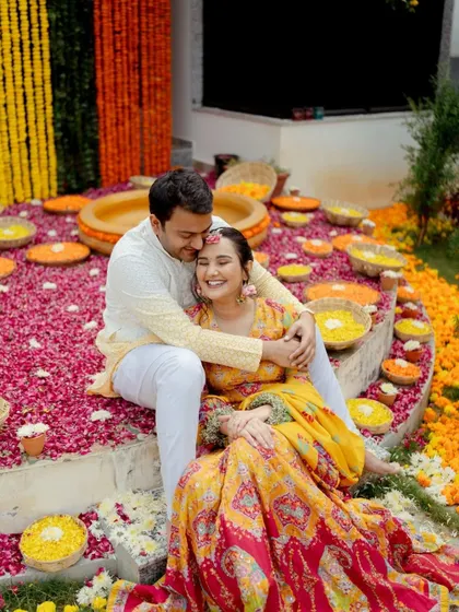 The couple shares a warm embrace amidst a sea of colorful flowers. The bride's joyful laugh makes this a heartwarming and candid shot.