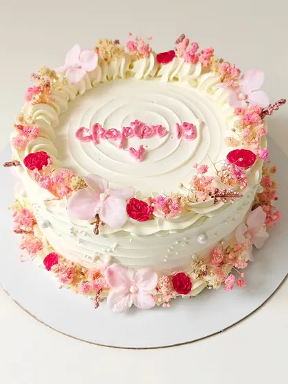 "Chapter 19." A beautiful vintage-style cake decorated with a wreath of dried baby's breath and other delicate flowers. The soft, rustic look is perfect for a special birthday.