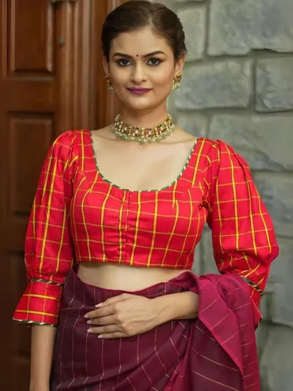 A red and yellow checkered blouse is paired with a simple gold choker, a perfect look for a daytime festive event.