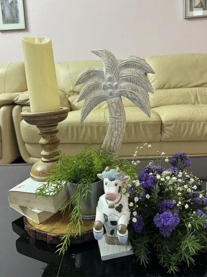 A rustic centerpiece for the ONEderland party, featuring a miniature cow, a stack of books, a wooden candle holder, and fresh florals on a wood slice base.