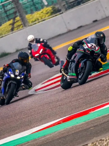 A pack of riders, including a Yamaha R15 and a Kawasaki ZX-10R, navigate a corner together, showcasing the mix of bikes on track.