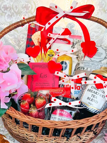 The perfect romantic gesture, this 'Breakfast in Bed' basket is designed for a luxurious morning. It includes fresh strawberries, premium English breakfast tea, cherry jam, Nutella, and salted caramel hot chocolate, all beautifully arranged in a classic wicker basket with red and pink accents.